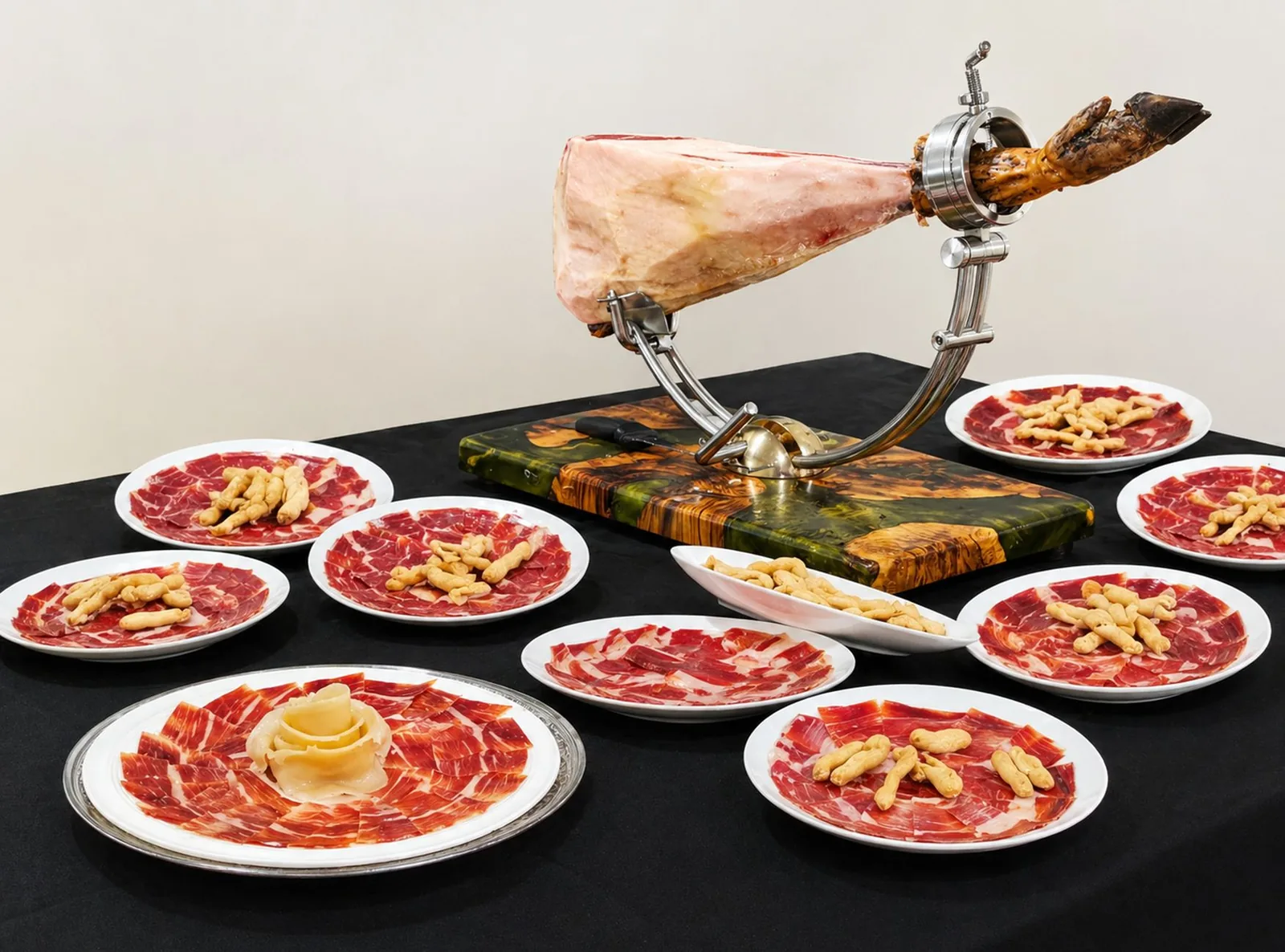 Un jambon ibérique sur son jamonero, sabot noir visible, et des assiettes de tranches coupées à la main