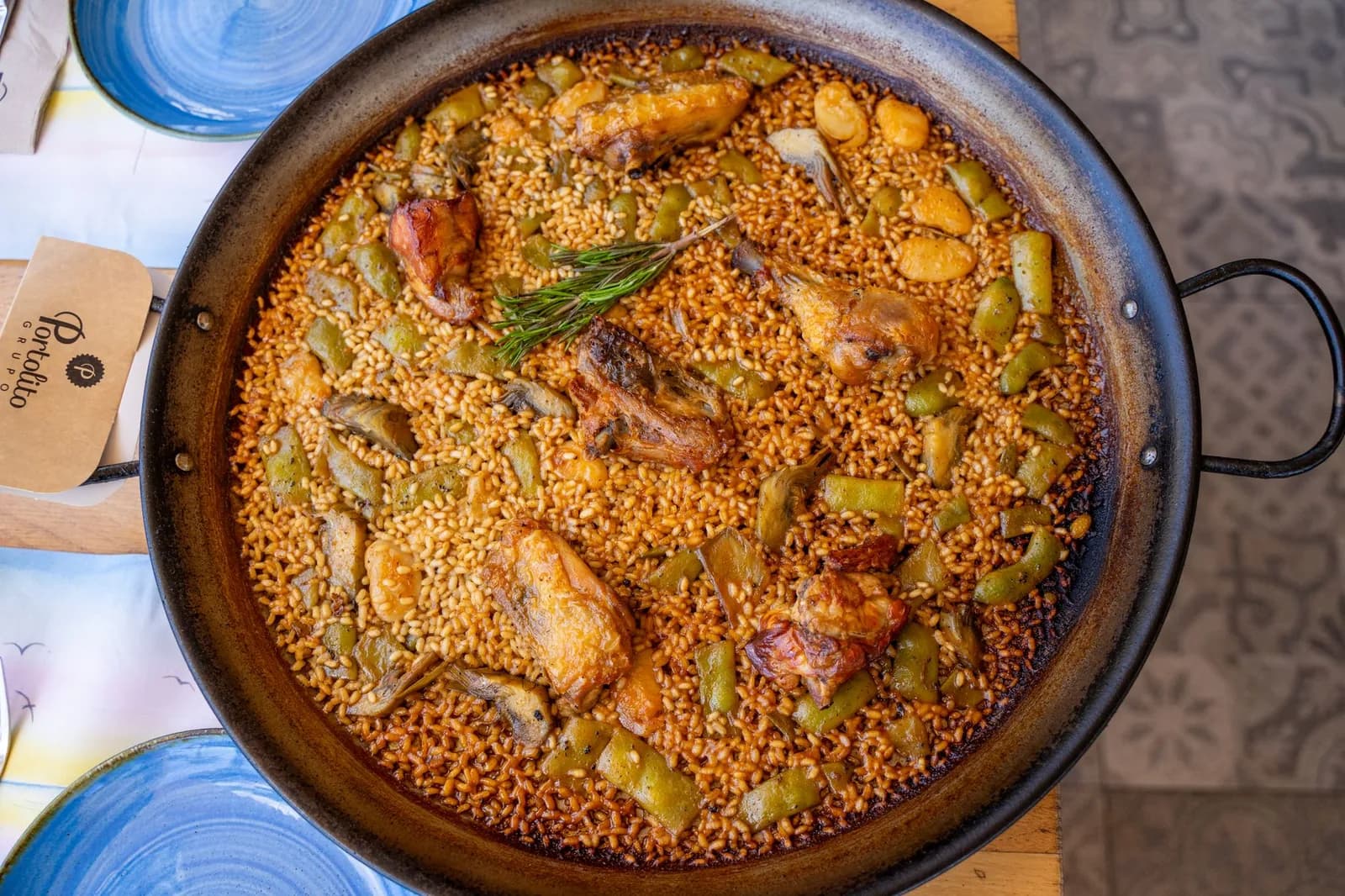 Une paella valenciana dans sa poêle, au poulet, au lapin, aux haricots plats et au garrofó