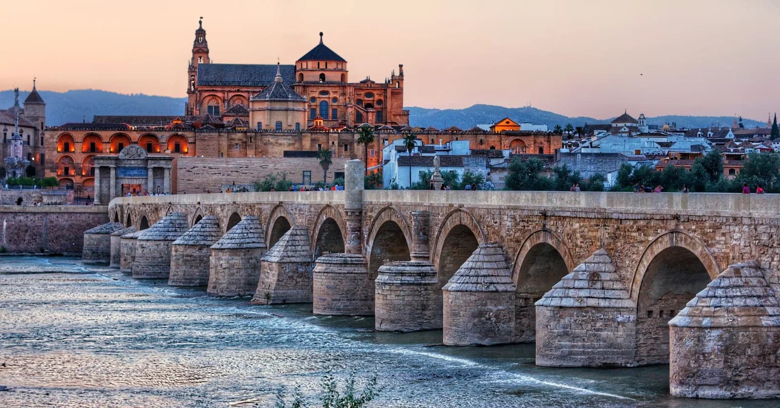 Le pont romain de Cordoue au crépuscule, la Mezquita-cathédrale illuminée derrière, sur le Guadalquivir