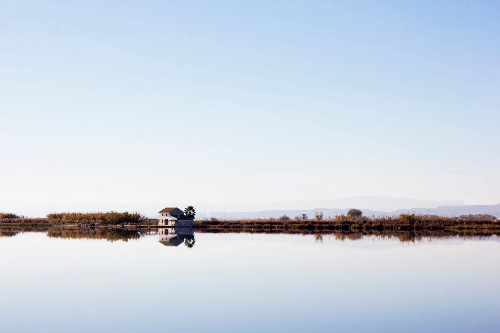 Une barraca blanche isolée au bord des rizières inondées de l'Albufera, près de Valence, reflétée dans l'eau immobile