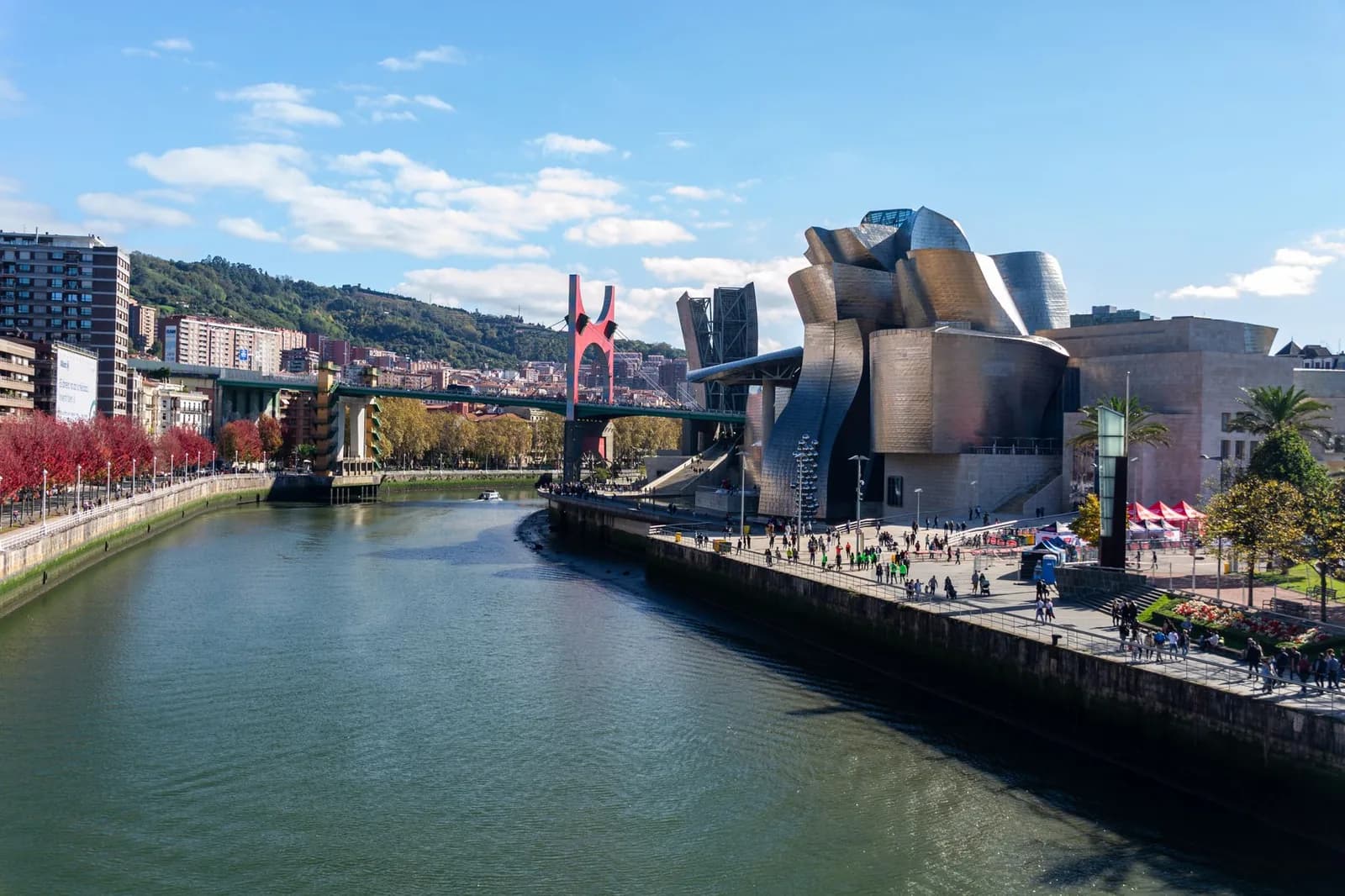 Le musée Guggenheim de Bilbao au bord du Nervión, ses volumes de titane et l'arc rouge du pont de La Salve