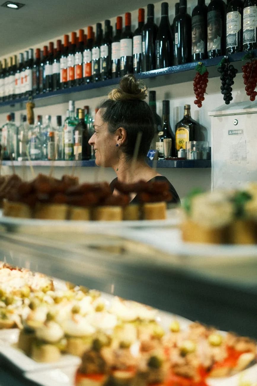 Le comptoir d'un bar à pintxos, ses plateaux de bouchées piquées de brochettes et ses bouteilles de rioja au-dessus